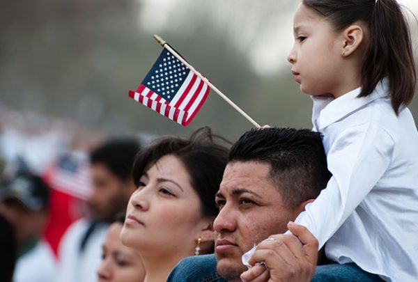 Immigrant carrying a little girl holding a US flag in her hand