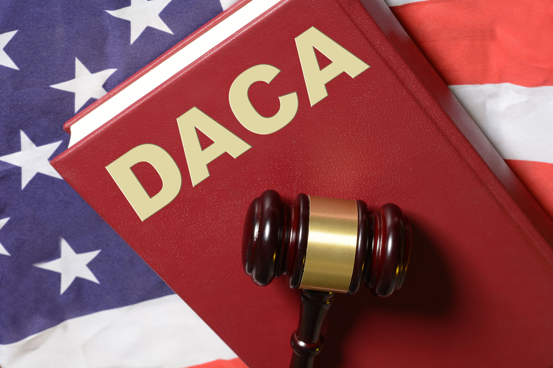 Libro rojo del programa DACA con un martillo encima sobre bandera de USA